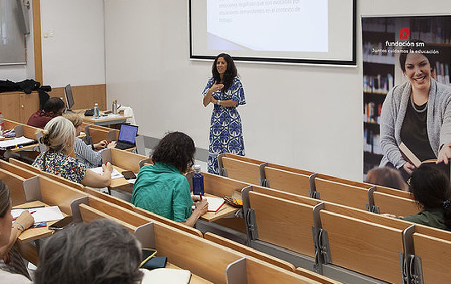 Imagen de una ponente dando una charla a alumnos en un aula.